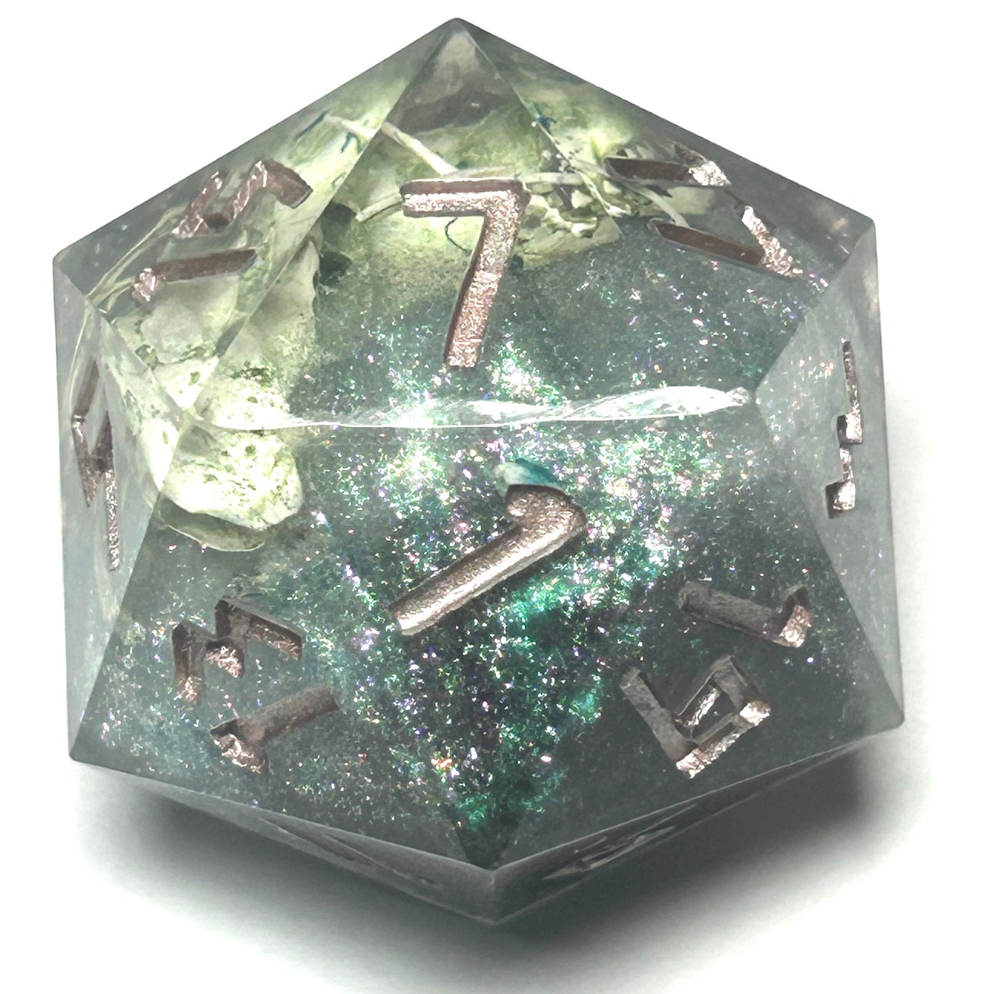 Close-up of a handmade 35mm resin D20 containing mouse bones, ethically sourced from owl pellets, with shimmering accents and gold inked numbers.