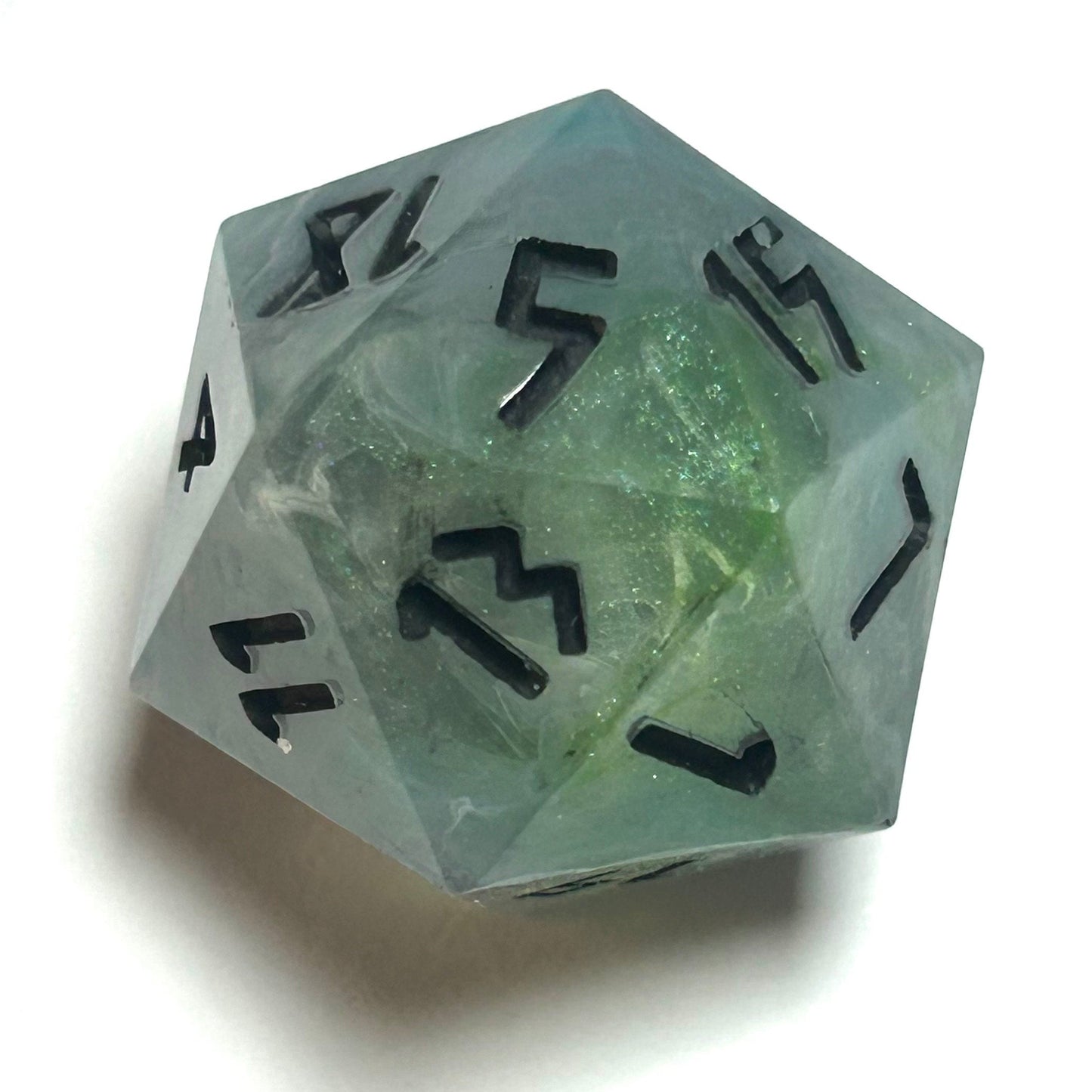 Close-up of D20 die from the Mistbourne handmade resin dice set, showing teal and gray marbling with black engraved numbers
