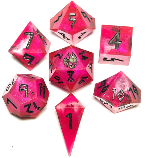 Handmade 7-piece pink and red resin dice set for tabletop RPGs, featuring marbled transparant white swirls with black numbers and glitter sparkling accents.